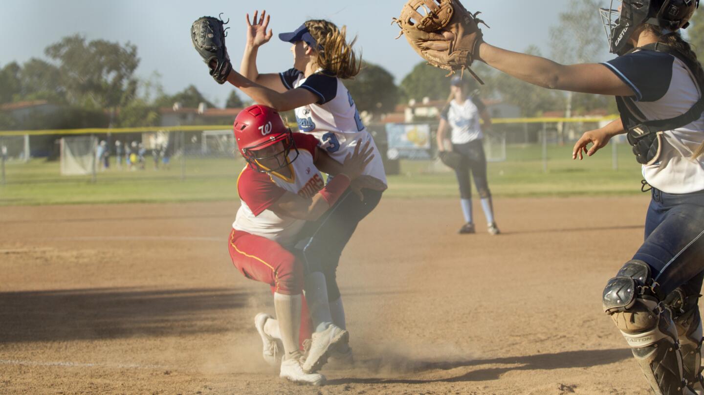 Corona del Mar High's Mallory McCrane, center, secures the pass to home plate as she collides with Woodbridge's Sofie Adams during the sixth inning in a Pacific Coast League game in Newport Beach on Wednesday. The head umpire ruled the play an interference on Mallory for blocking the plate. (Kevin Chang/ Daily Pilot)