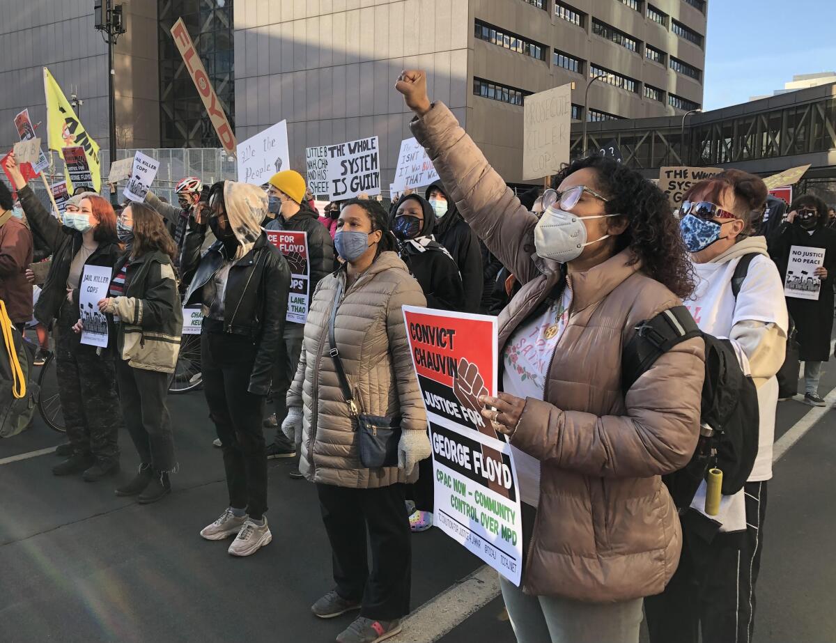 People wearing masks stand in lines holding signs.