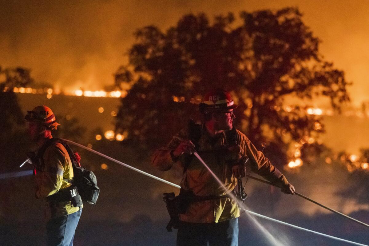 Firefighters use water hoses against a fire