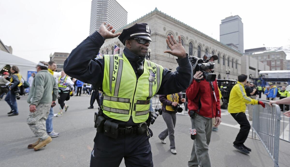 A Boston police officer clears Boylston Street following an explosion at the finish line of the 2013 Boston Marathon.