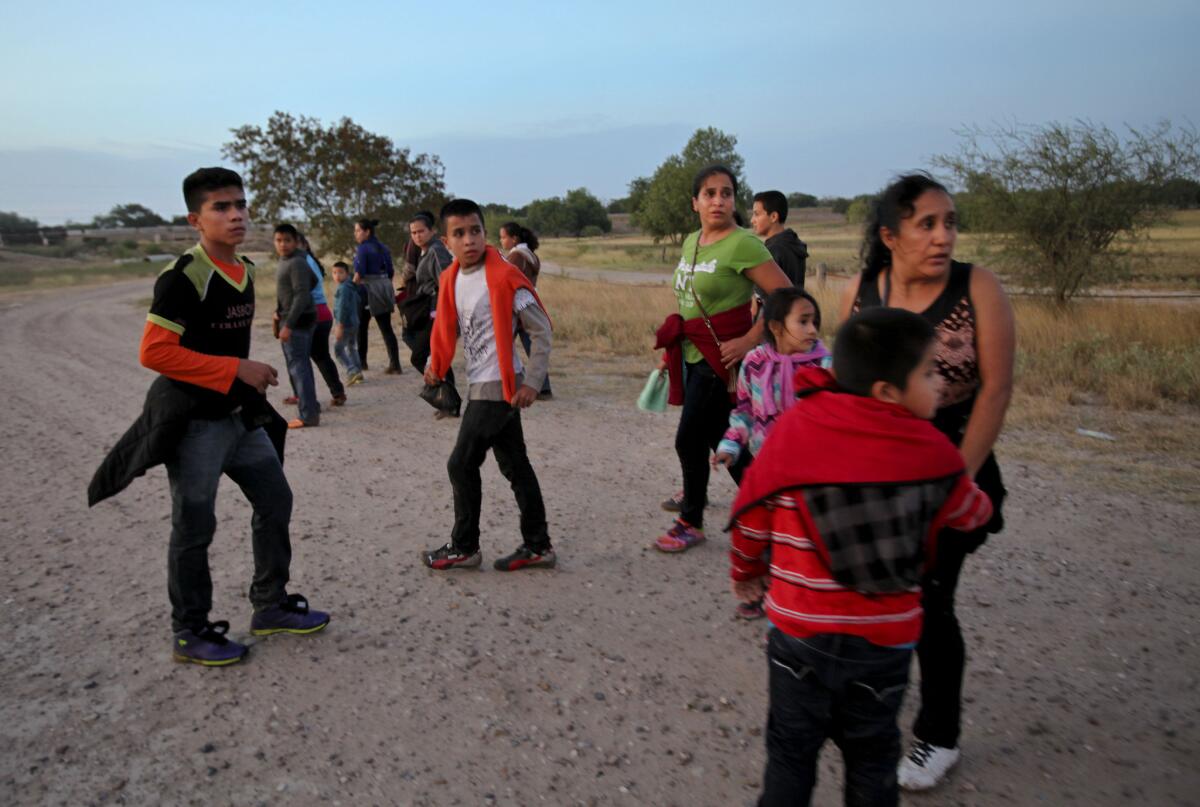 来自危地马拉的移民转身面对一名未在图中显示的地方执法人员。2014年，在他们穿越德州麦卡伦附近的南里奥格兰德后，执法人员做出指示。