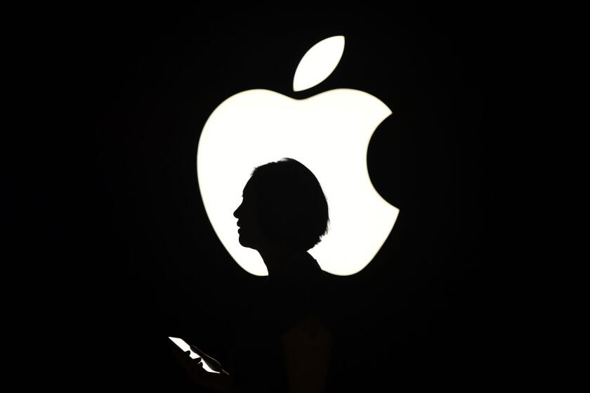 A reporter walks by an Apple logo during a media event in San Francisco, California on Sept. 9, 2015.