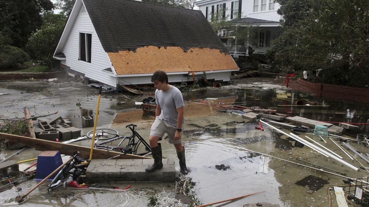 Resident Joseph Eudi looks over flood debris and storm damage at a home on East Front Street in New Bern, N.C.