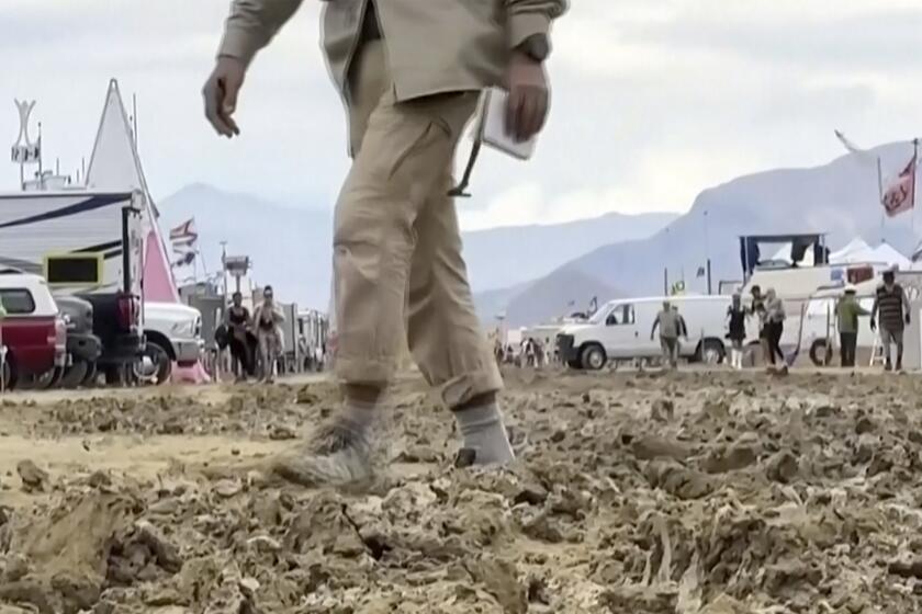 a man walks through mud at the Burning Man festival site 