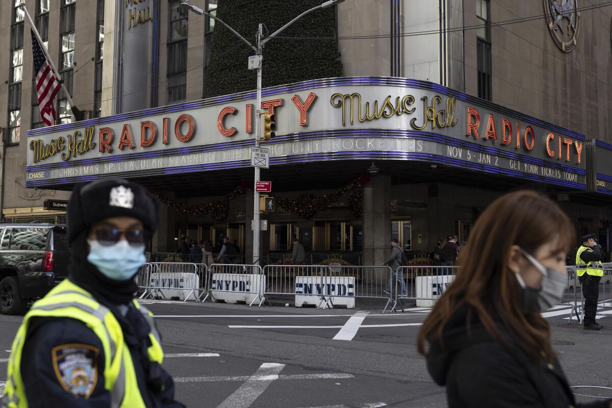 People stand in front of Radio City Music Hall, its entrance behind NYPD barricades. 