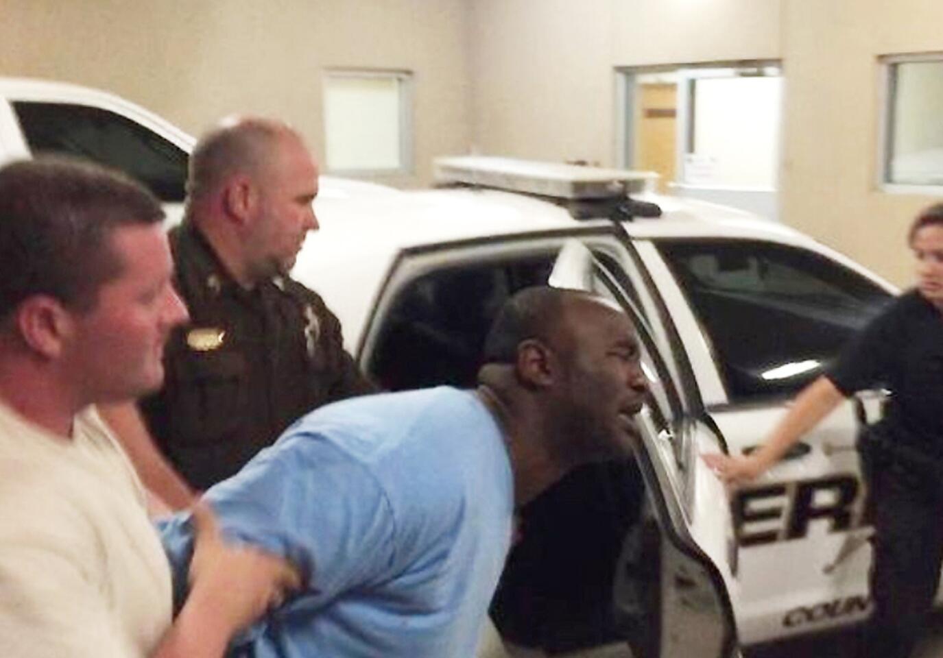 Officers lead Curtis Banks, center, into the Mississippi Highway Patrol office in Hattiesburg, Miss., early Sunday after he was arrested in connection with the fatal shooting of two officers.