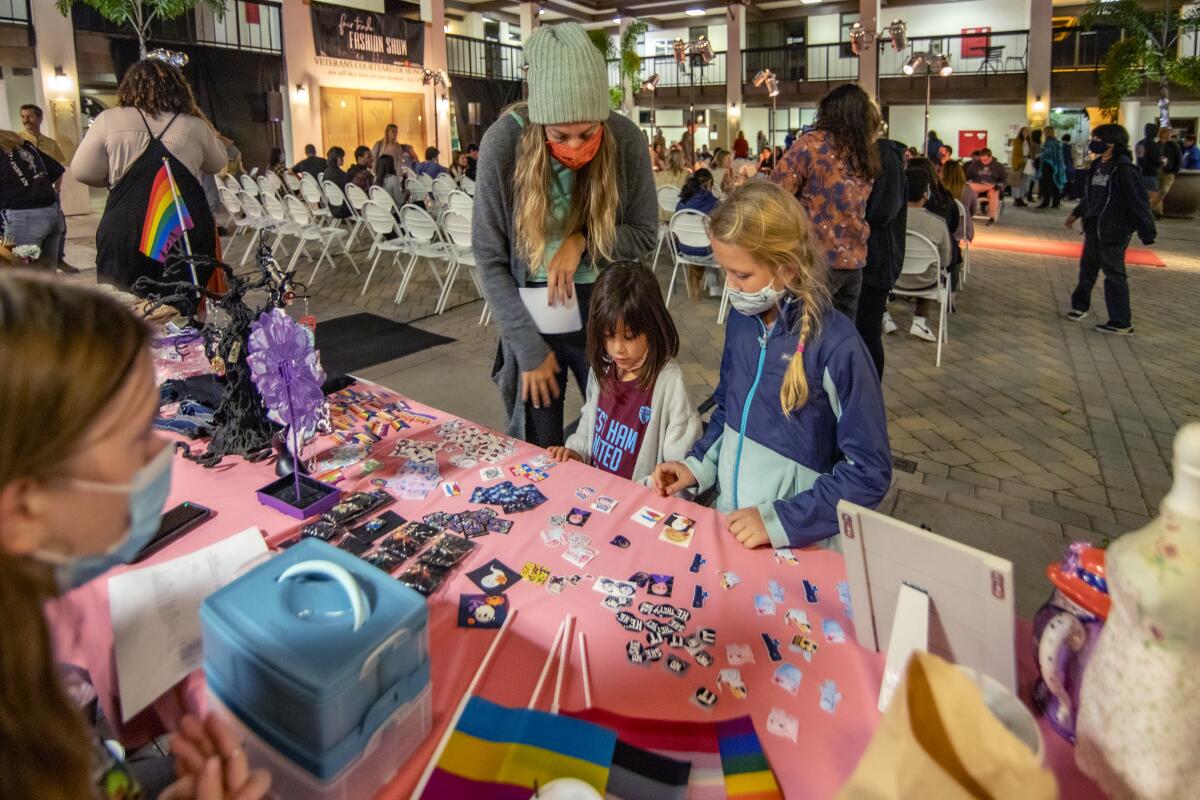 Bethany Anderson and daughters Alivia and Anabel shop at the OPIA Upcycling booth Thursday at a Fair Trade Fashion Show.