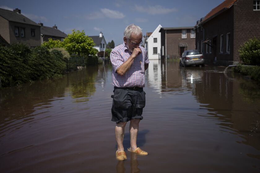 Wiel de Bie, 75, stands outside his flooded home in the town of Brommelen, Netherlands, Saturday, July 17, 2021. In the southern Dutch province of Limburg, which also has been hit hard by flooding, troops piled sandbags to strengthen a 1.1-kilometer (0.7 mile) stretch of dike along the Maas River, and police helped evacuate low-lying neighborhoods. (AP Photo/Bram Janssen)