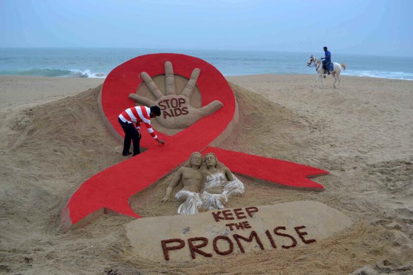 Indian sandartist Sudersan Pattnaik gives the final touches to a sand sculpture on the eve of World AIDS Day, an annual event to raise awareness about HIV/AIDS.