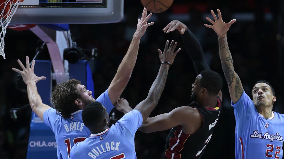 Miami Heat guard Dwyane Wade, center, passes over Spencer Hawes, left, Reggie Bullock and Matt Barnes during the first half Sunday at Staples Center.
