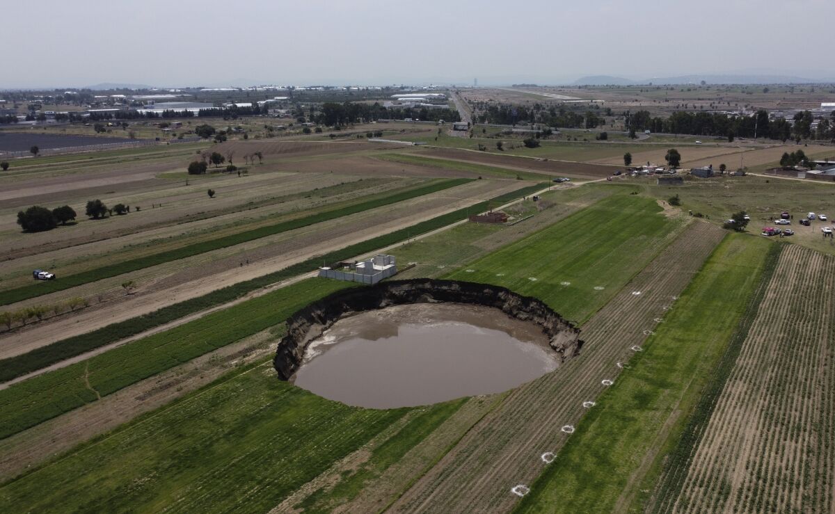 A water filled sinkhole grows in Zacatapec, on the outskirts of Puebla, Mexico, Tuesday, June 1, 2021. The massive water-filled sinkhole continues swallowing farmers' fields in the central Mexican state of Puebla. Authorities say an underground river is responsible. (AP Photo/Pablo Spencer)