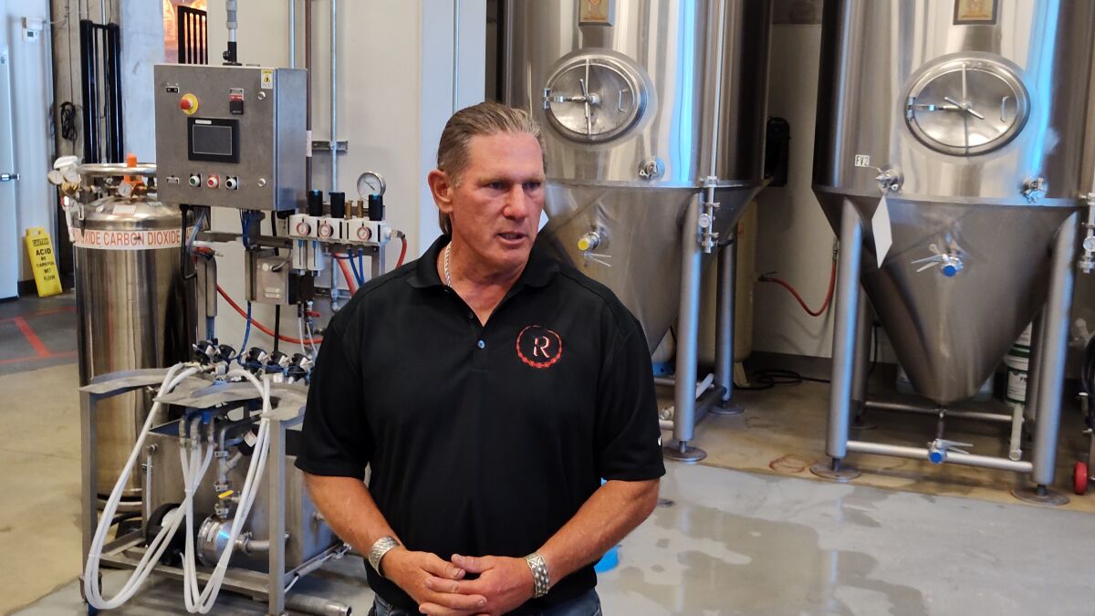 Man stands inside beer brewery.