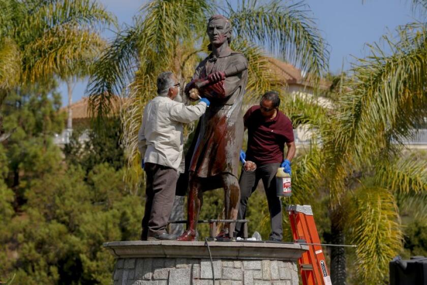 Workers clean paint off Christopher Columbus statue at Discovery Park in Chula Vista