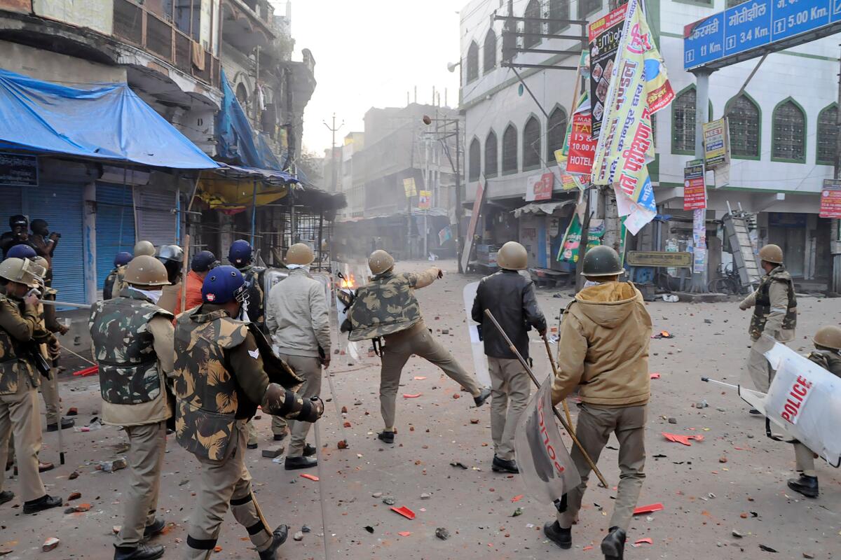 A police officer throws stones toward protesters in Kanpur during demonstrations against India's new citizenship law on Dec. 21.