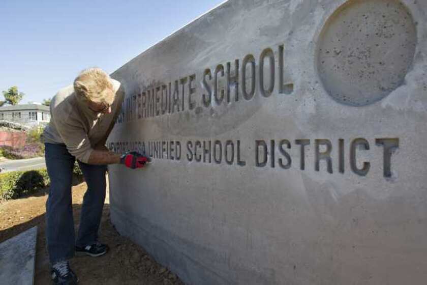 A contractor prepares a concrete sign for painting at Ensign Intermediate School in Newport Beach in 2013. The Newport-Mesa Unified School District board of trustees voted Tuesday to make several changes to the campus, including new fencing, new parking areas and changes to landscaping.