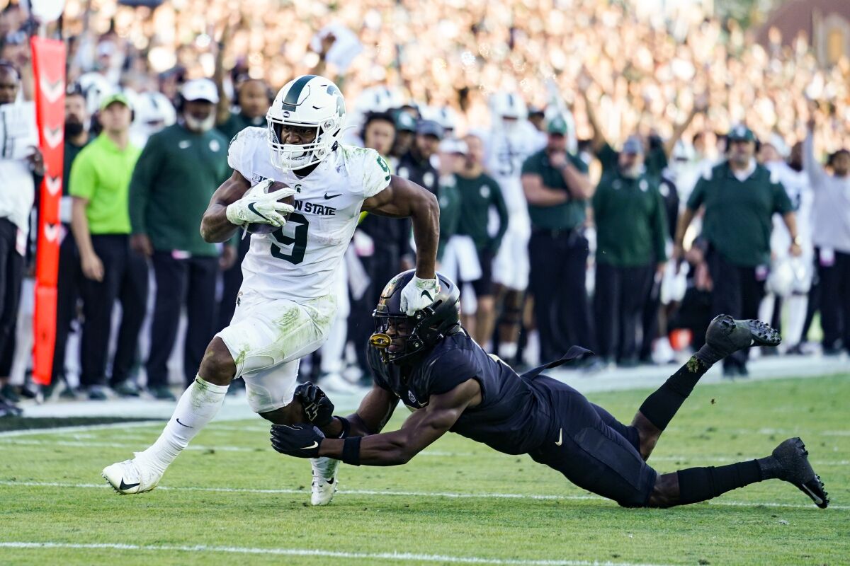 Michigan State running back Kenneth Walker III (9) breaks the tackle of Purdue cornerback Jamari Brown (7) on his way to a touchdown during the first half of an NCAA college football game in West Lafayette, Ind., Saturday, Nov. 6, 2021. (AP Photo/Michael Conroy)