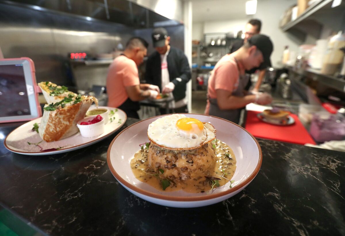The kitchen crew at Breezy restaurant finish a big order including the adobo burrito and loco moco.