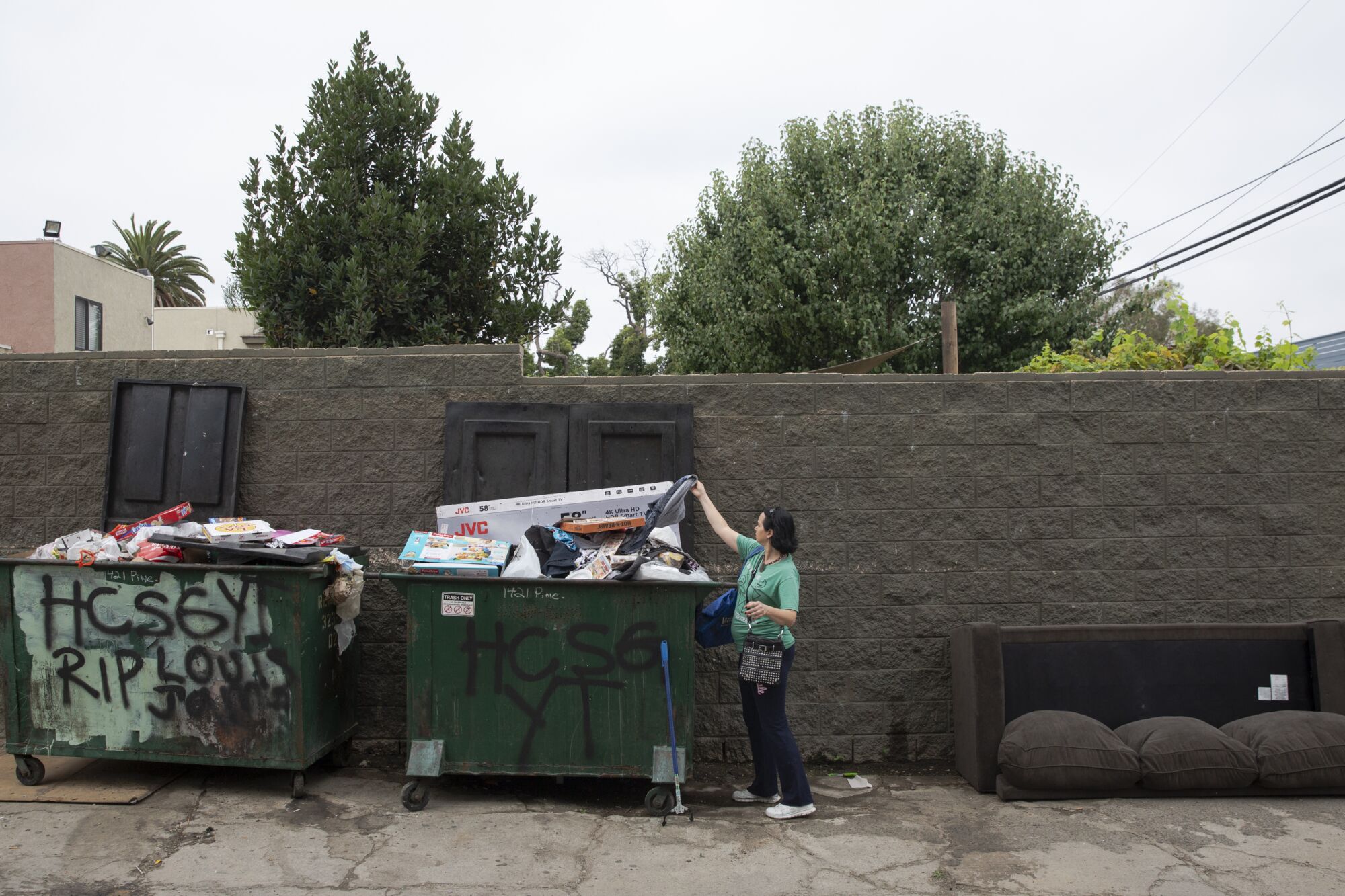 Amber Elizabeth Stevens reaches into a dumpster for salvageable items.