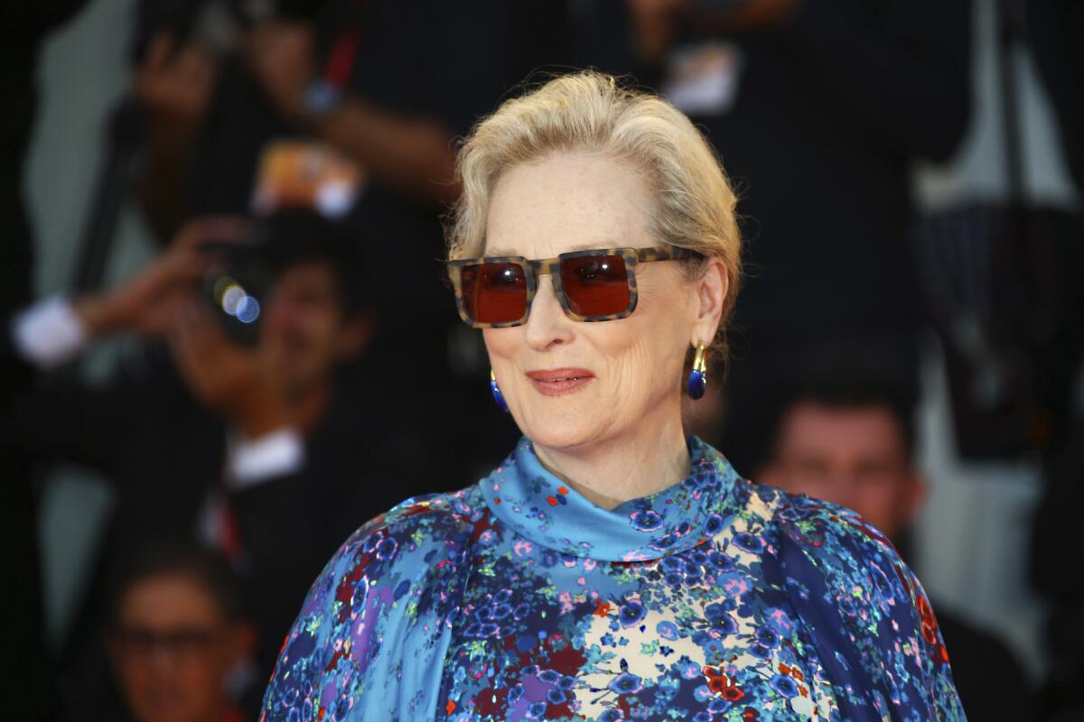 A woman with blond hair pulled back wearing sunglasses and a floral dress