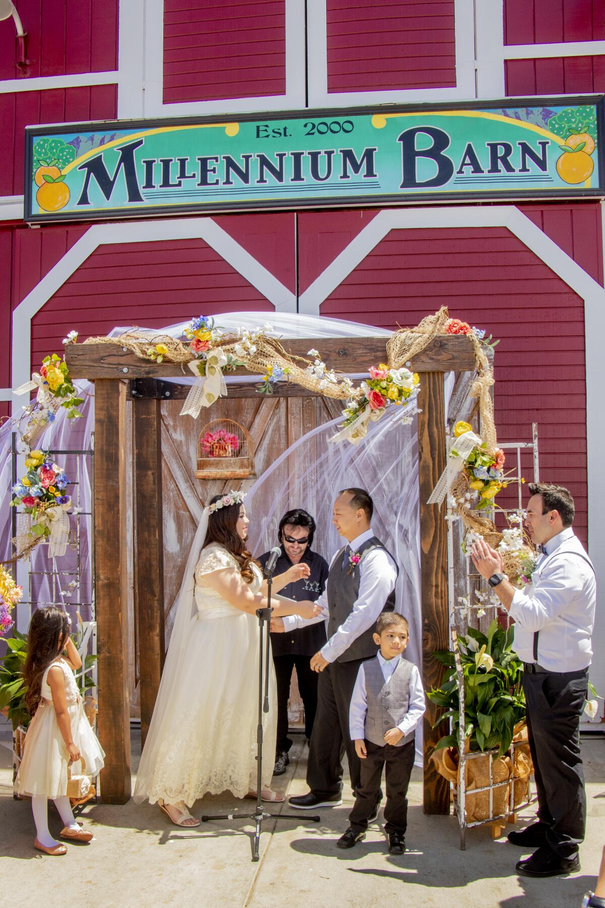 Minister Phil Shane of Universal Life Church presides at the wedding of Leslie Leong and Michael Nguyen at the Millennium Barn. To their right is ring bearer Christopher Bran.