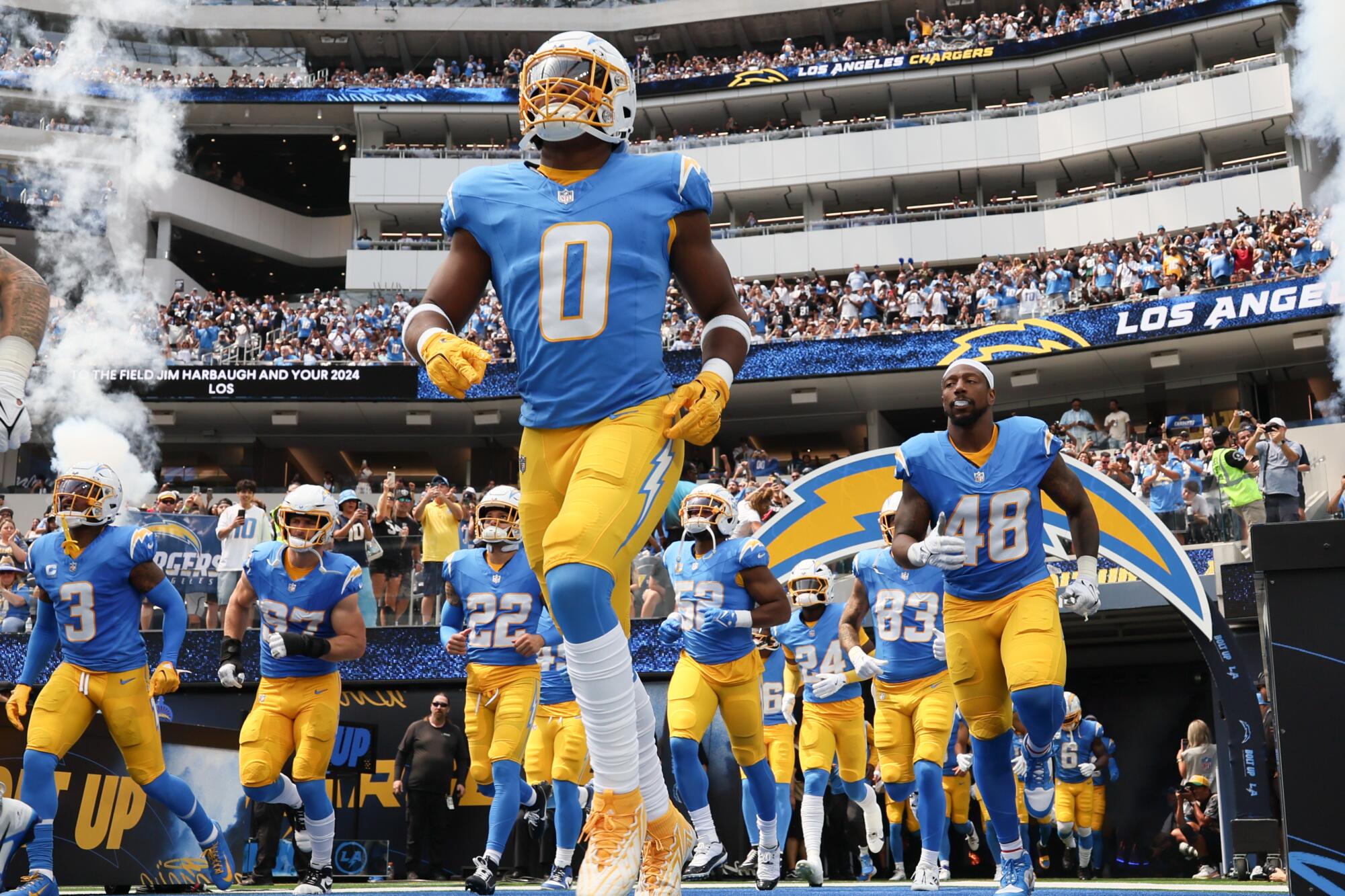 Linebacker Daiyan Henley and the rest of the Chargers run onto the field at SoFi Stadium before a game against the Raiders.