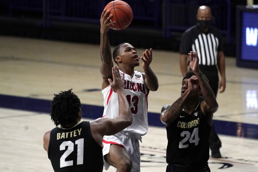 Arizona guard James Akinjo drives between Colorado forward Evan Battey and guard Eli Parquet.