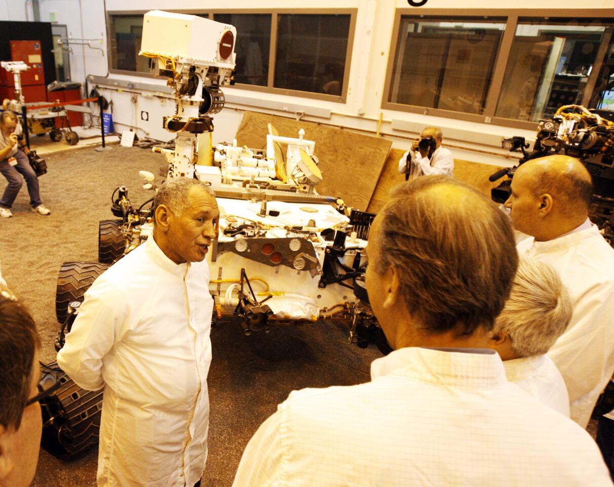 NASA Administrator Charles Bolden talks with scientist and engineers at JPL next to a duplicate of the Mars Rover Curiosity at JPL on Wednesday, February 22, 2012. The room is bathed in light that is similar to the light on the martian planet.