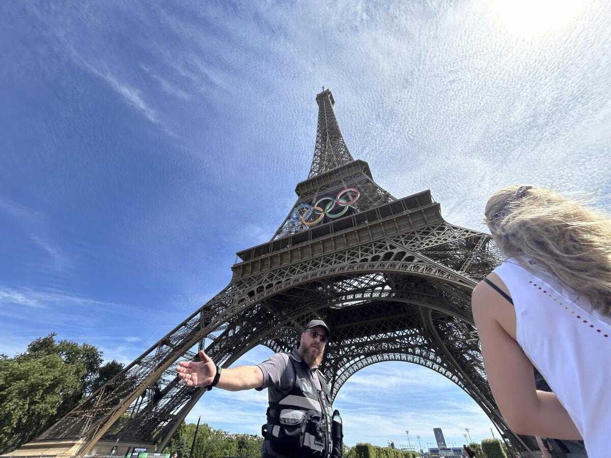 A police officer moves a person away from the Eiffel Tower.