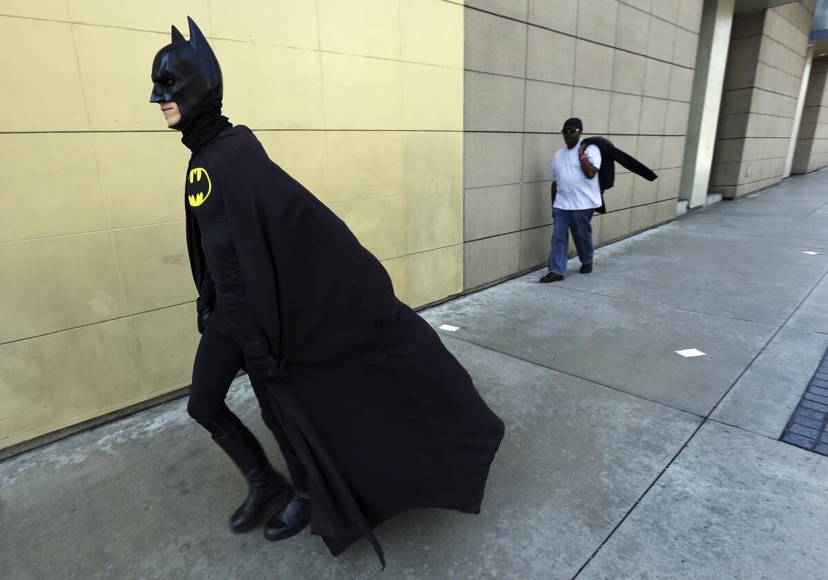 With cape flowing and pointy ears perked, Austin Franklin heads up Highland Avenue to his job entertaining tourists and posing for pictures as Batman.