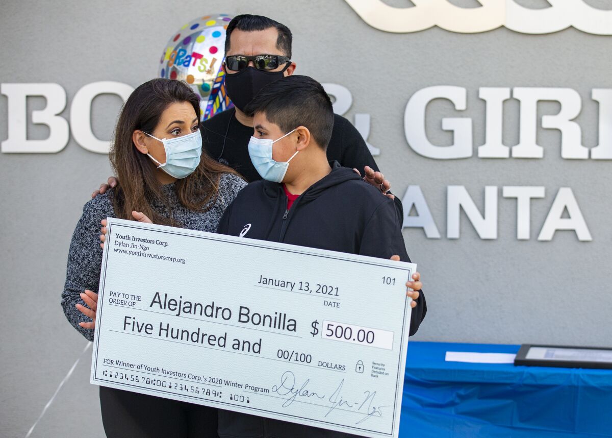 Rocio and Juan Bonilla embrace their son Alejandro, 11, after he received a check for $500 on Wednesday.