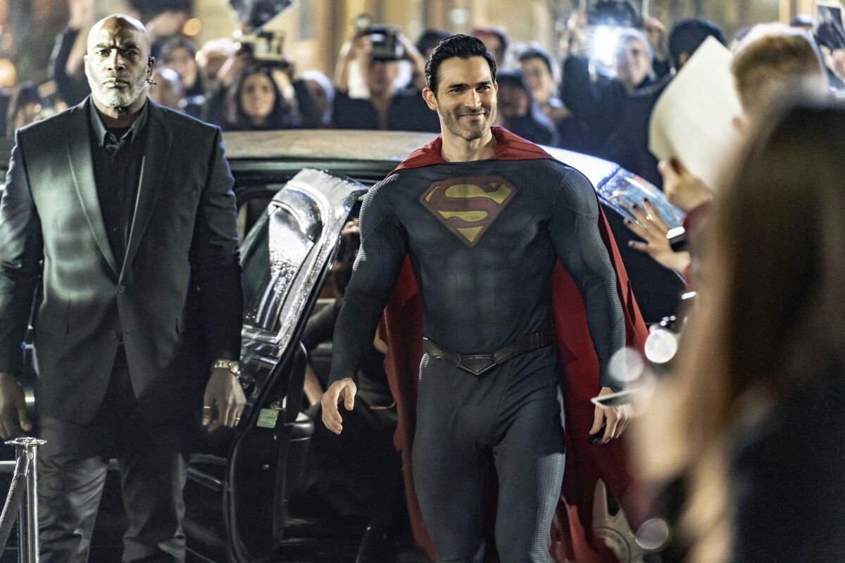 Superman steps out of a car amid a crowd of paparazzi.