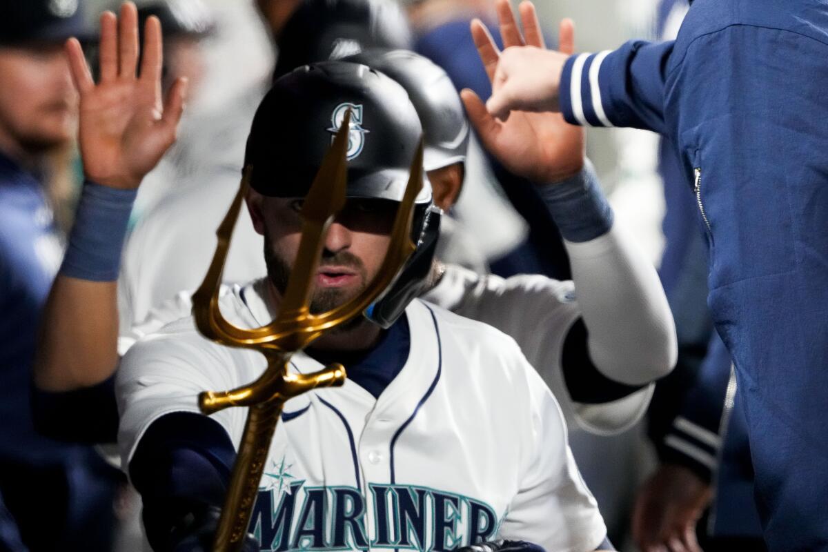 Seattle Mariners' Mitch Haniger points a trident in the dugout after hitting a two-run home run against the Cincinnati Reds during the third inning of a baseball game Monday, April 15, 2024, in Seattle. (AP Photo/Lindsey Wasson)