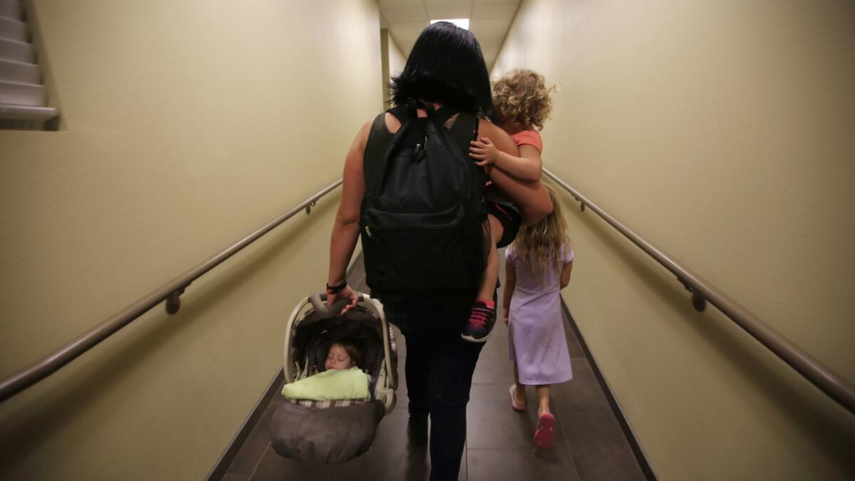 A mother takes her children to their room at the San Fernando Valley Rescue Mission last November. More than 11% of Los Angeles County families on welfare assistance are homeless, according to state statistics.