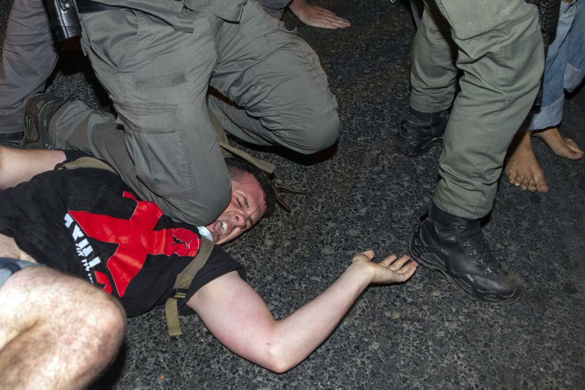 Israeli police officer puts his knee on a demonstrator
