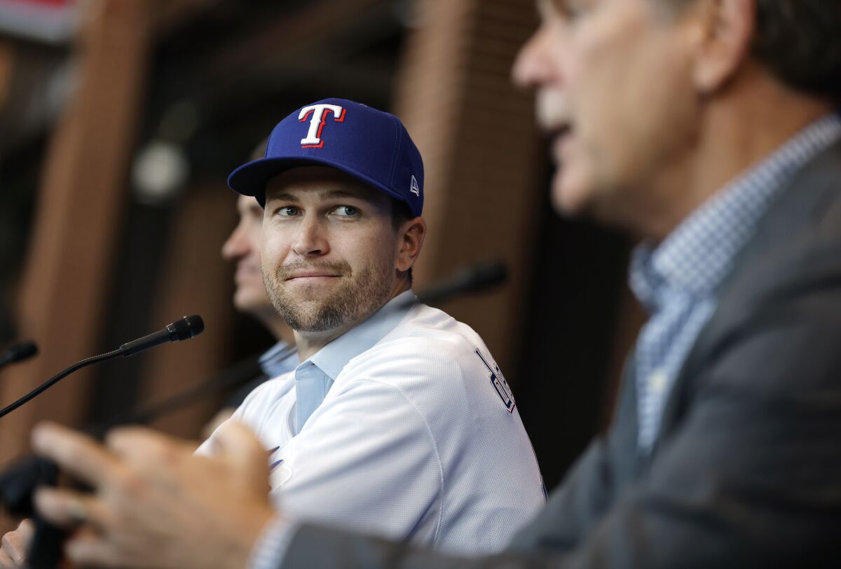 Texas Rangers starting pitcher Jacob deGrom, left, listens to new manger Bruce Bochy after trying on his new jersey during a press conference at Globe Life Field in Arlington, Texas, Thursday, Dec. 8, 2022. Jacob deGrom is the latest big signing for the Rangers in their effort to turn things around, with his $185 million, five-year deal getting completed last Friday even before baseball winter meetings.(Tom Fox/The Dallas Morning News via AP)