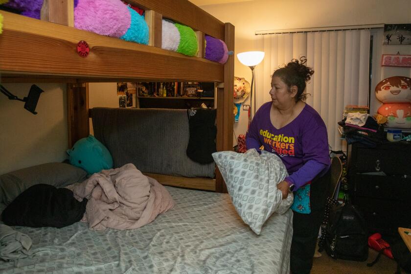 LOS ANGELES, CA - MARCH 22: Yadira Martinez, 53, is works for LAUSD as special education assistant, her 24-year-old son Leonardo hernandez, who also works for district as building and grounds worker and 14-year-old daughter Samantha Rendon in small two bedroom apartment in Huntington Park. Martinez fixes bunkbed she share with her daughter at apartment on Wednesday, March 22, 2023 in Los Angeles, CA. (Irfan Khan / Los Angeles Times)
