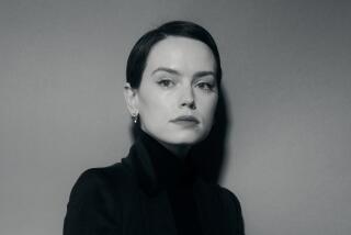 Daisy Ridley wears a long black coat with her hair slicked back in a moody photo