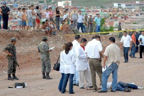 Mexican forensics stand around the body of a young man who was killed in Renato Vega district, Culiacan city, in the Mexican state of Sinaloa. Officials said that in addition five policemen were killed in the cities of Campeche and Juarez.