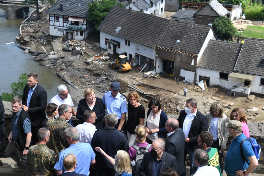 German Chancellor Angela Merkel, rear third left, and the Governor of the German state of Rhineland-Palatinate, Malu Dreyer, rear fifth left, are seen on a bridge in Schuld, western Germany, Sunday, July 18, 2021 during their visit in the flood-ravaged areas to survey the damage and meet survivors. After days of extreme downpours causing devastating floods in Germany and other parts of western Europe the death toll has risen. (Christof Stache/Pool Photo via AP)