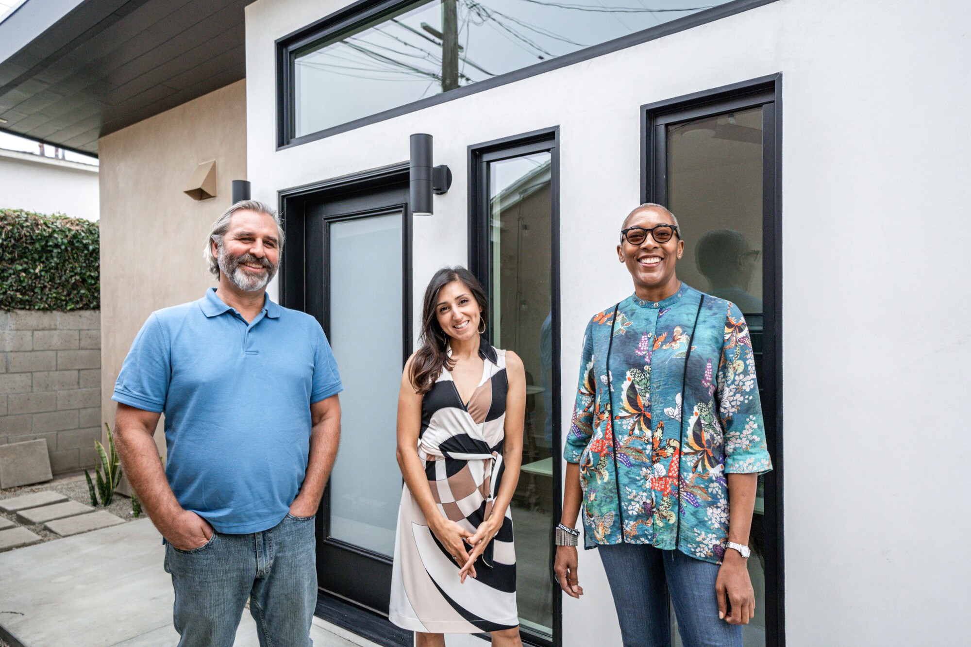 Three people stand in front of an ADU 