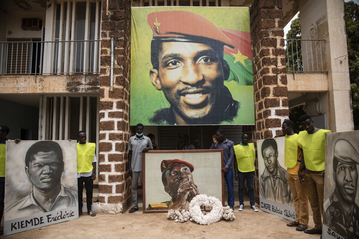 People gather for a wreath laying ceremony in front of the building where Thomas Sankara was assassinated in 1987 in Ouagadougou, Burkina Faso, Wednesday April 6, 2022, after the verdict of the trial of his assassination. A Burkina Faso military tribunal sentenced ex-President Blaise Compaore to life imprisonment for complicity in the murder of his predecessor Thomas Sankara and for undermining state security. Compaore was tried in absentia as he has been in exile in Ivory Coast since he was toppled from power by a popular uprising in 2014. (AP Photo/Sophie Garcia)