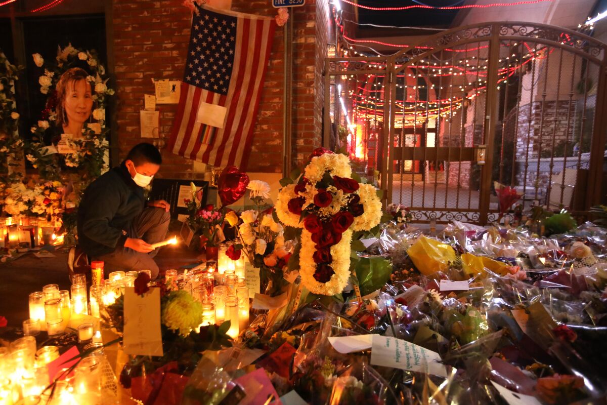 Flowers and candles form a sidewalk memorial.