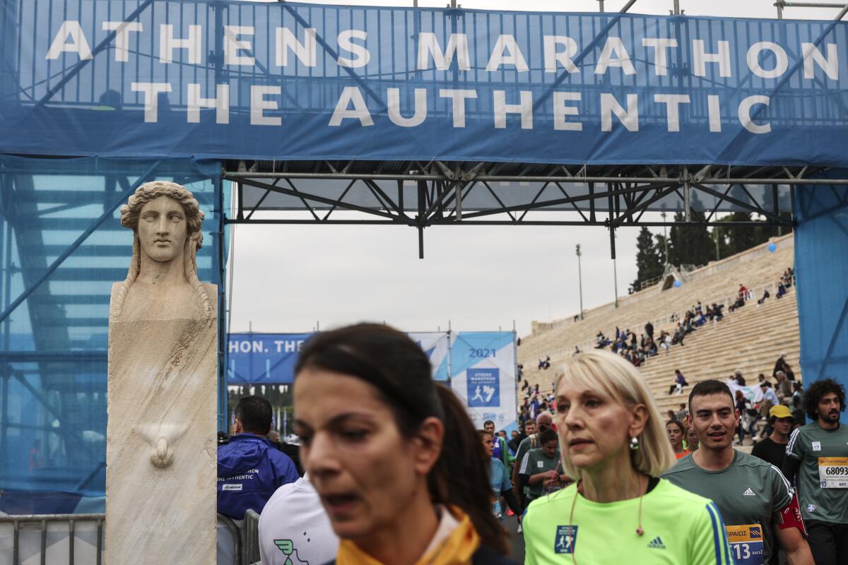 Runners cross the finish line in a 10 kilometer (6.2 mile) road race during the 38th Athens Marathon in Athens, Greece, Sunday, Nov. 14, 2021. (AP Photo/Yorgos Karahalis)