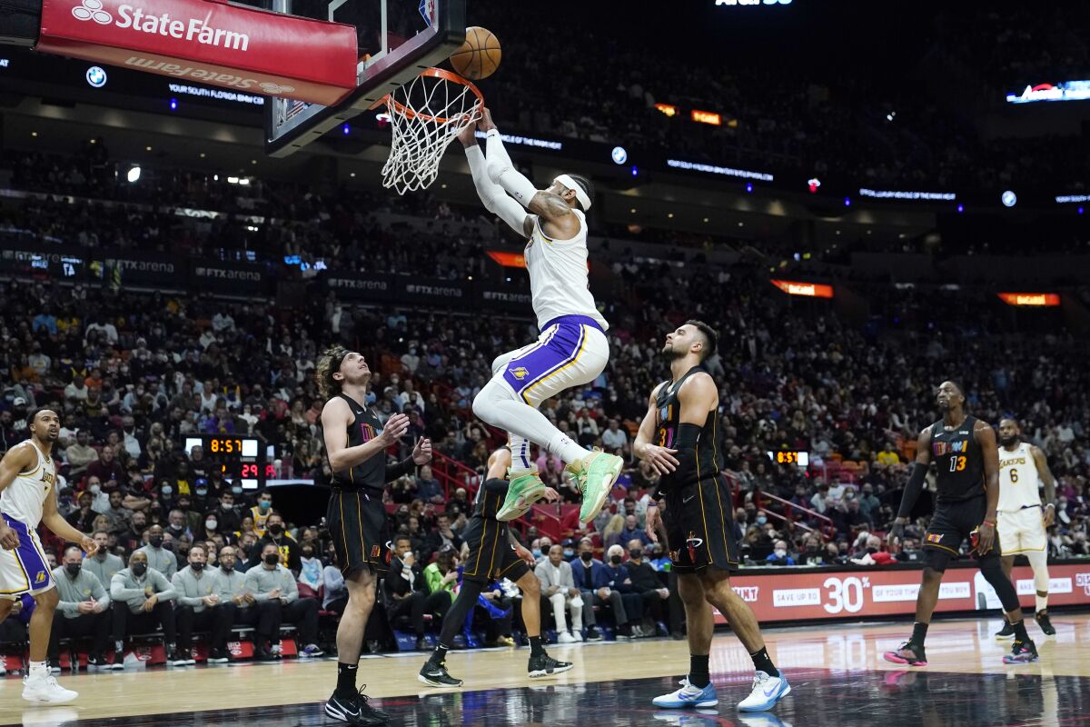 Lakers forward Carmelo Anthony, center, misses an attempted dunk over Miami Heat guards Kyle Guy and Max Strus.