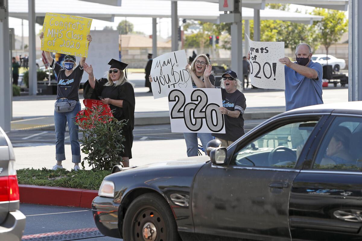 Faculty and staff members show their support for graduates during a drive-through graduation ceremony for Marina High.