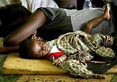 Ju Sieno, 7 months, lies beside his mother Hawa David, 19, at the National Stadium of Monrovia, Liberia, where thousands have come for safely from the recent fighting.