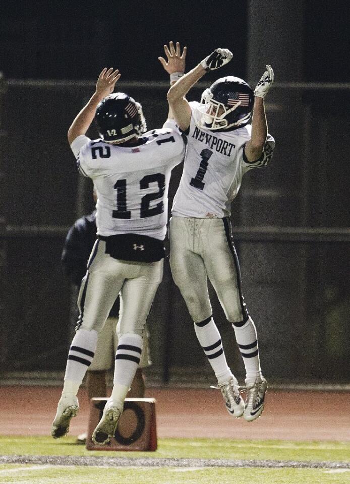 Newport Harbor's Cole Norris (12) celebrates with Quest Truxton after he scored a touchdown in the first half against Huntington Beach on Friday.
