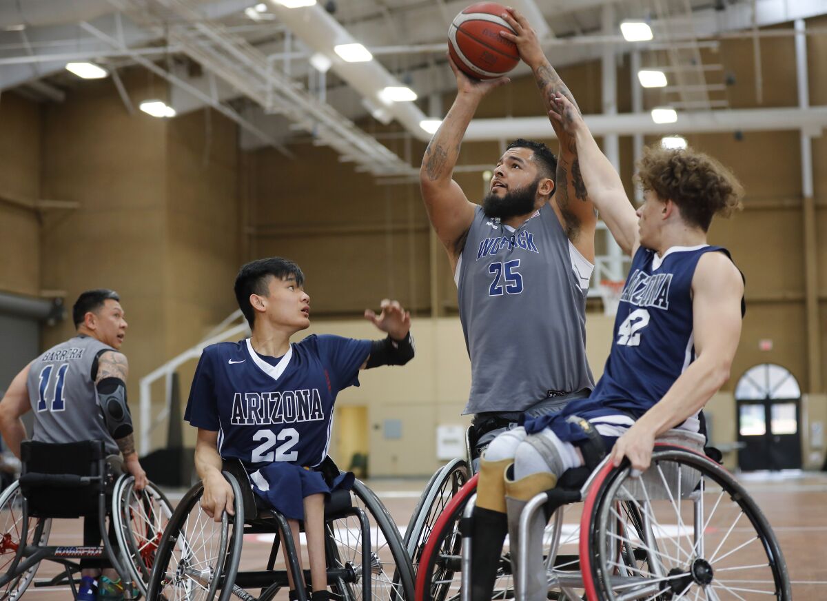 Jorge Salazar, center, of the Naval Medical Center San Diego Wolfpack shoots as Michael Seo, left, and Jackson Stone of the University of Arizona defend during the 4th Annual Brad Rich Invitational wheelchair basketball tournament at the Del Mar Fairgrounds on Feb. 9, 2020.