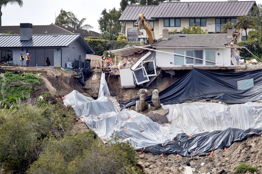 Newport Beach, CA - March 16: Windows and debris crash down the hillside as crews demolish the final remaining walls on a red-tagged Newport Beach home owned by an elderly woman at 1930 Galaxy Drive in Newport Beach after it was undermined from a landslide that fell into the Newport Back Bay from recent storms Thursday, March 16, 2023. (Allen J. Schaben / Los Angeles Times)
