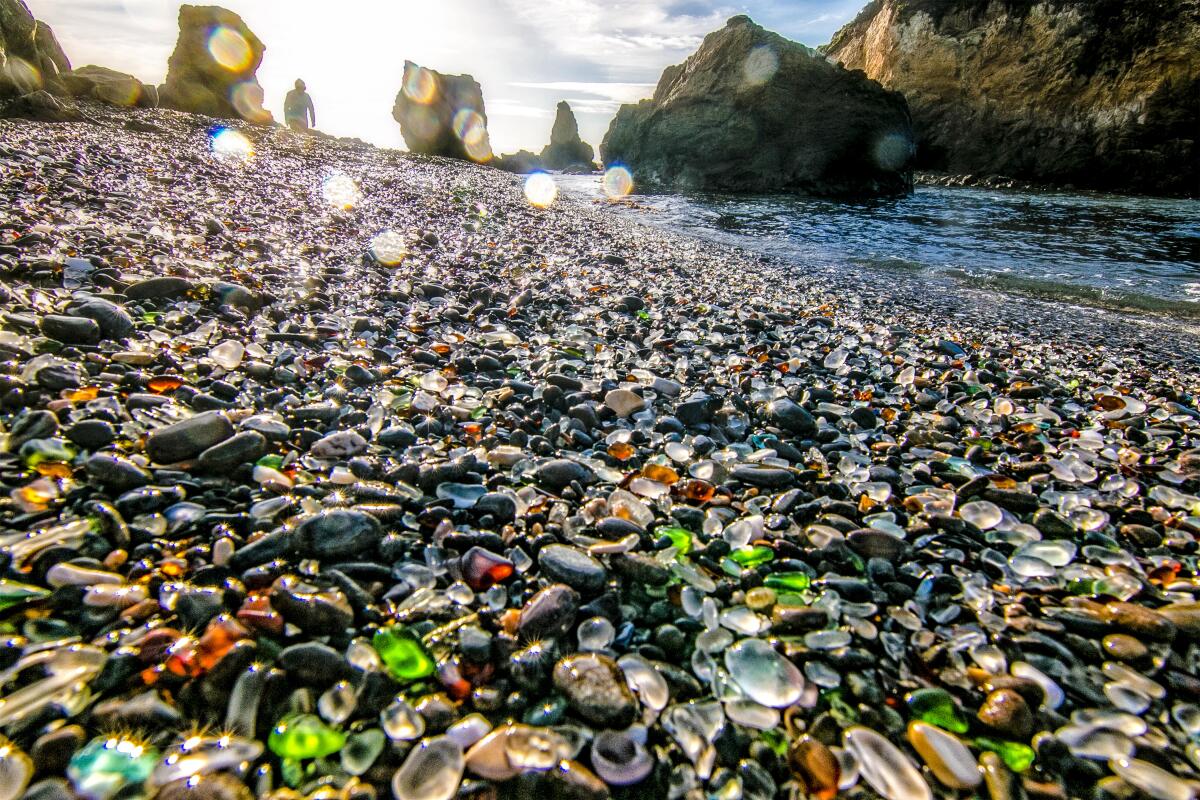 Seaglass covers the sand, with large boulders jutting out of the nearby Pacific Ocean.